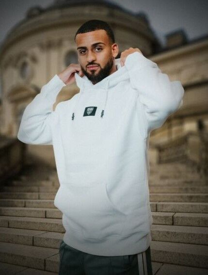 Josha Vagnoman trägt einen weißen Hoodie mit schwarzem VfB Wappen in der Mitte 