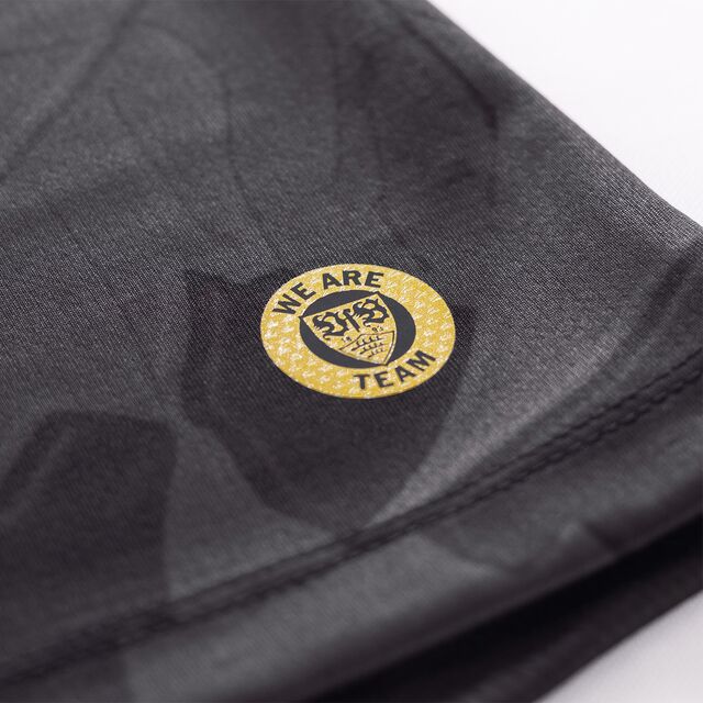 Nahaufnahme des goldenen, runden VfB Wappens mit der Aufschrift We Are Team auf dem Auswärtstrikot schwarz 25/26