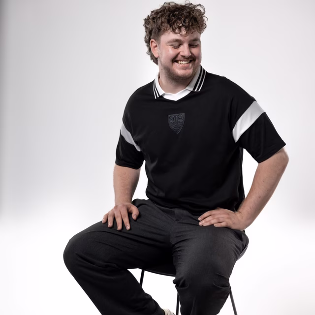 Schwarzes Polo mit schwarzem VfB Wappen in der Mitte und weißem Kragen 