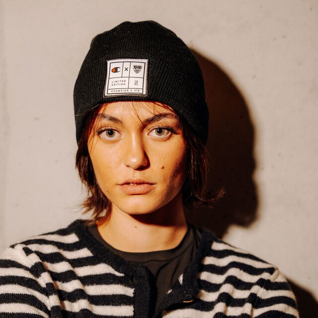 weibliches Model trägt die Champion x VfB Beanie  in Schwarz und schaut in die Kamera