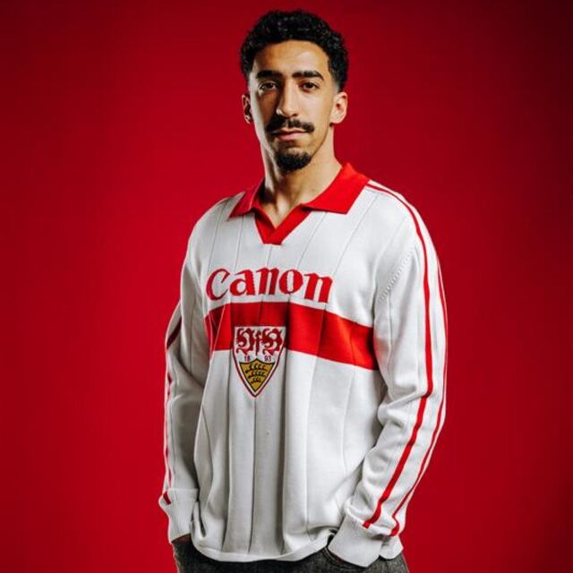 Tiago Tomas trägt das VfB Poloshirt Trikot Strick. Langarm Trikot in weiß mit rotem Brustring, rotem Polo-Kragen, großem VfB Wappen in der Mitte und Schriftzug Canon
