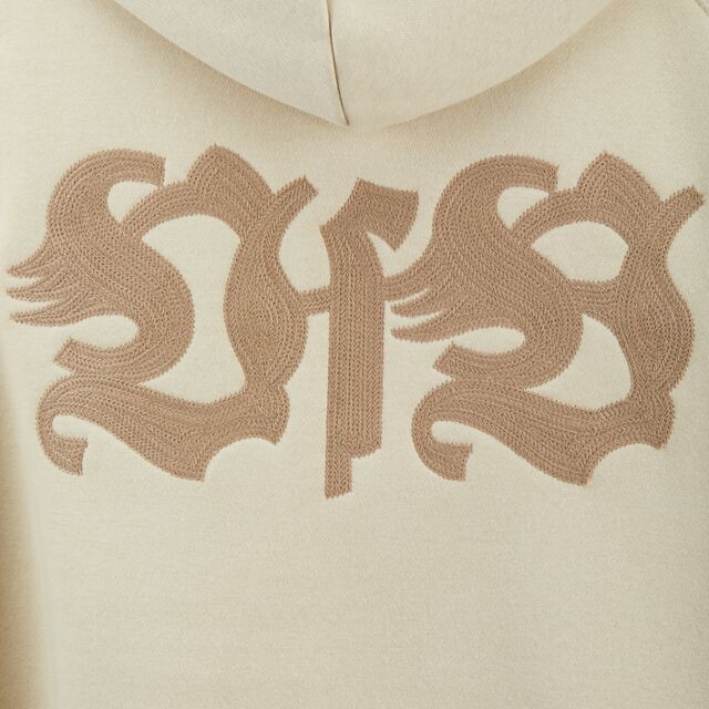 Nahaufnahme des beigefarbenen VfB Schriftzugs auf dem VfB Hoodie Tradition