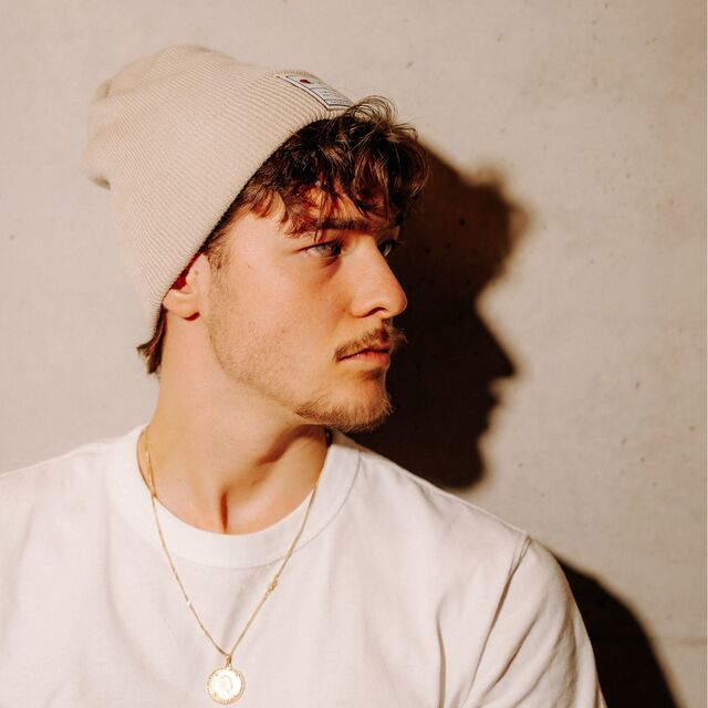 männliches Model trägt die Champion x VfB Beanie in Beige und schaut zur Seite