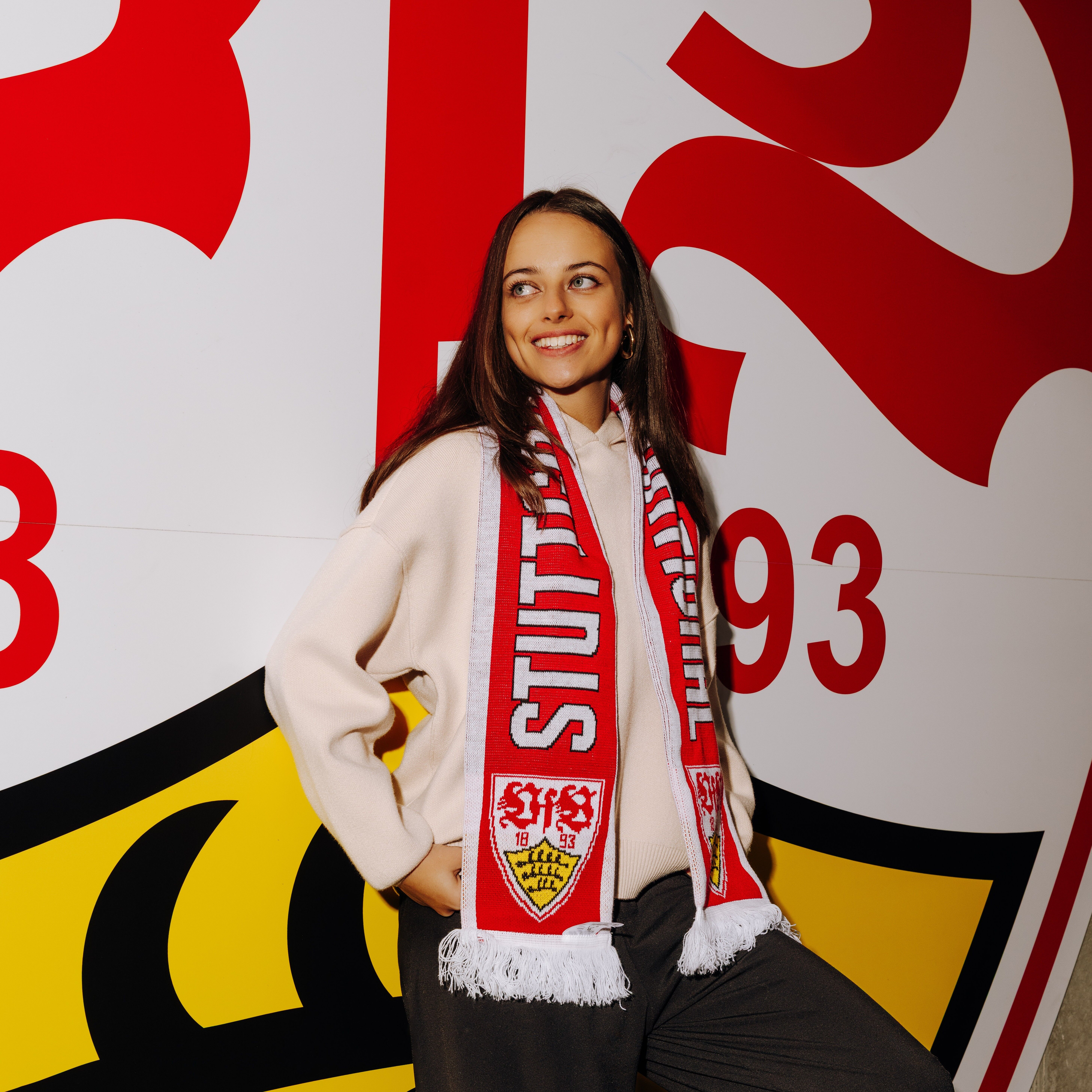 Model steht vor großem VfB Wappen und trägt den VfB Schal Stuttgart International 