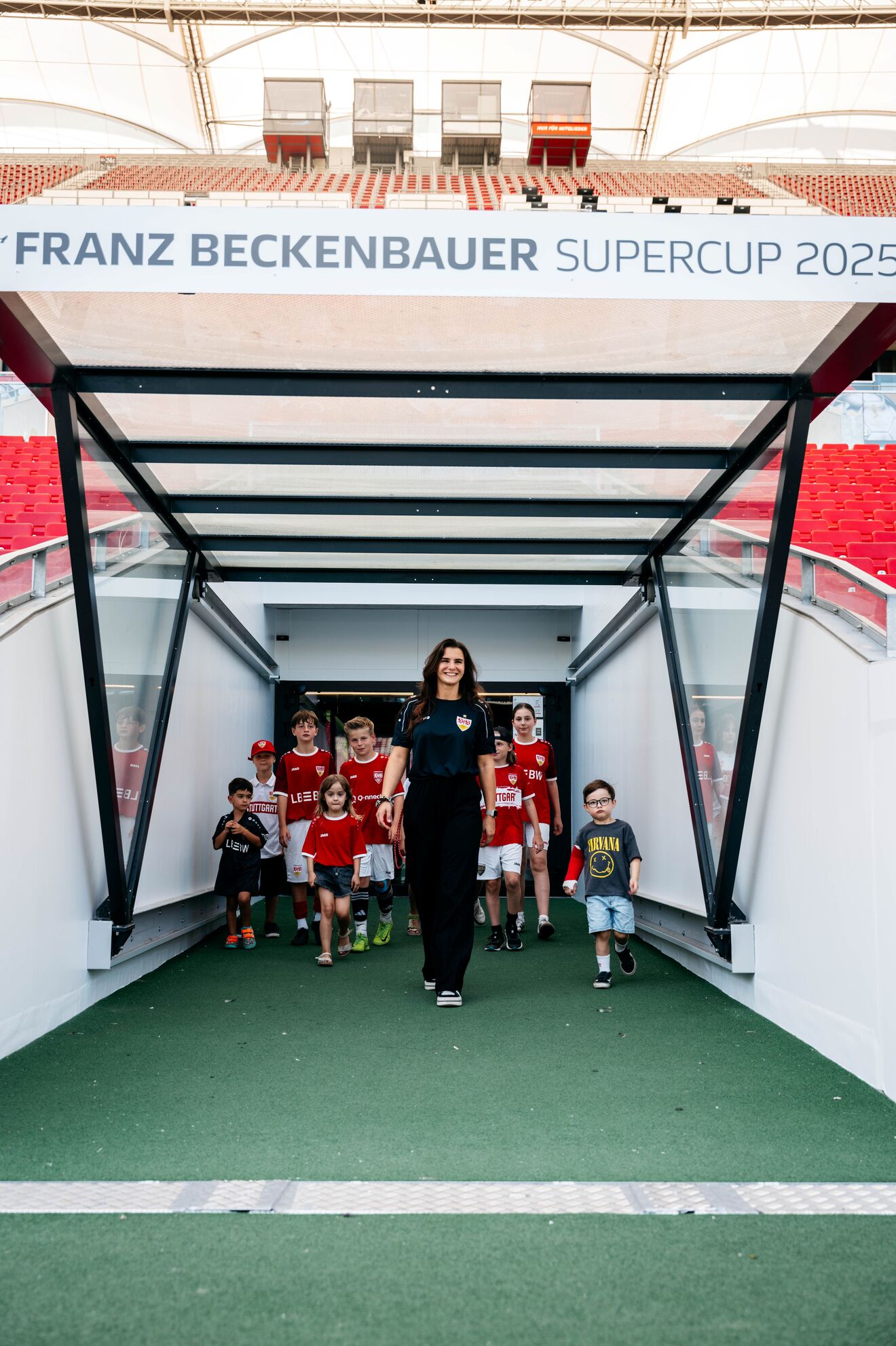 Eine Frau läuft mit mehreren Kindern durch den Stadiontunnel in das Stadion 