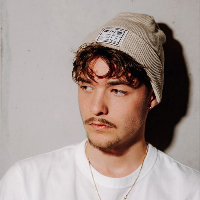 männliches Model trägt die Champion x VfB Beanie 3D beige und schaut zur Seite