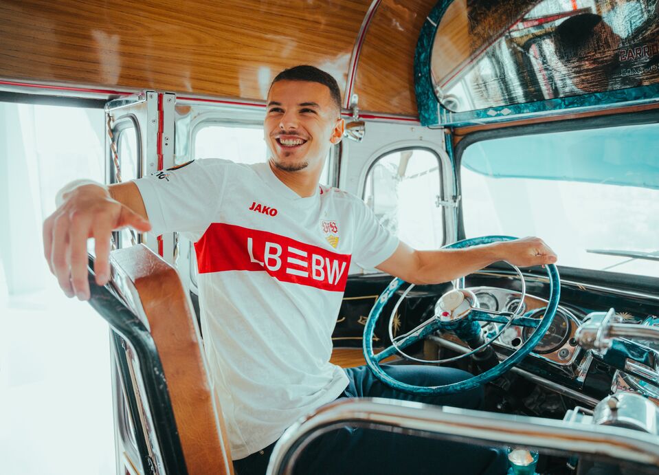 Spieler Bouanani sitz am Steuer eines Busses und trägt das Europa League Trikot 