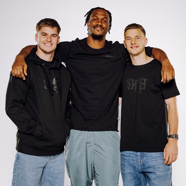 drei VfB Spieler tragen schwarze VfB Kleidung