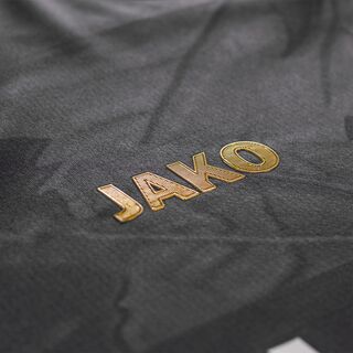 Nahaufnahme des goldenen JAKO Schriftzugs auf dem Trikot