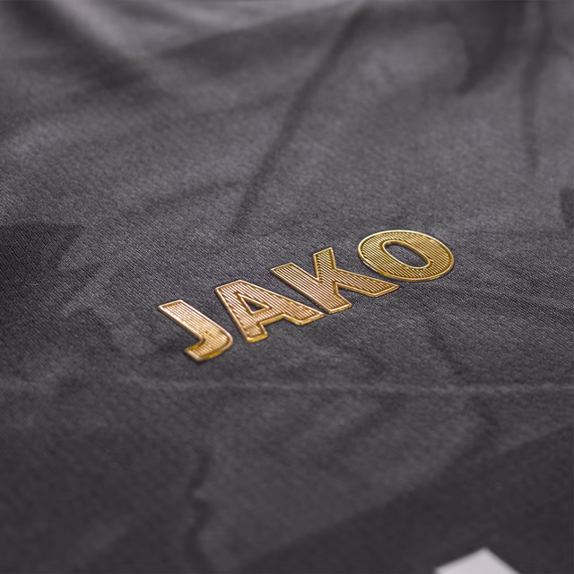 Nahaufnahme des goldenen JAKO Schriftzugs auf dem Trikot