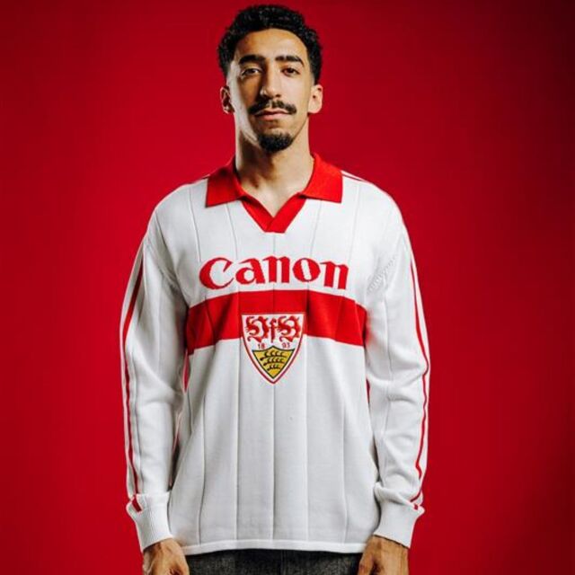 Tiago Tomas trägt das VfB Poloshirt Trikot Strick. Langarm Trikot in weiß mit rotem Brustring, rotem Polo-Kragen, großem VfB Wappen in der Mitte und Schriftzug Canon