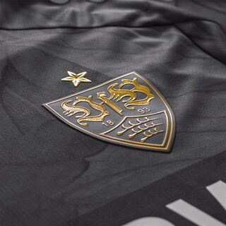Nahaufnahme des goldenen VfB Wappens auf dem Auswärtstrikot schwarz 25/26